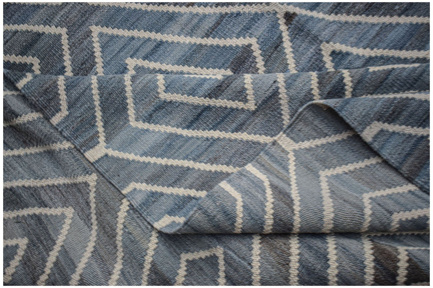 A handwoven Afghan Maimana kilim rug featuring a blue and white geometric pattern.