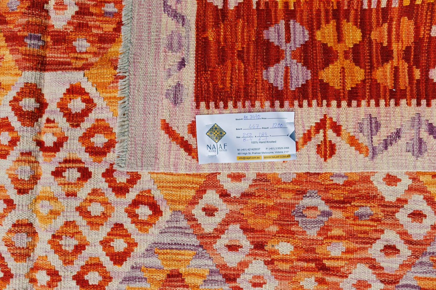 Handwoven Afghan Maimana kilim featuring a vibrant geometric pattern in orange, red, and purple.