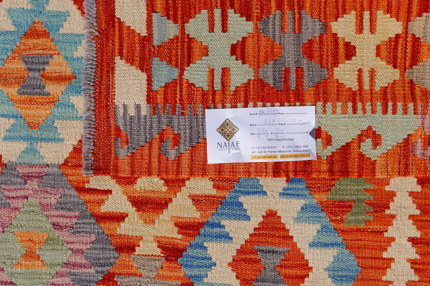 A handwoven Afghan Maimana kilim featuring vibrant geometric patterns in orange, blue, and cream.
