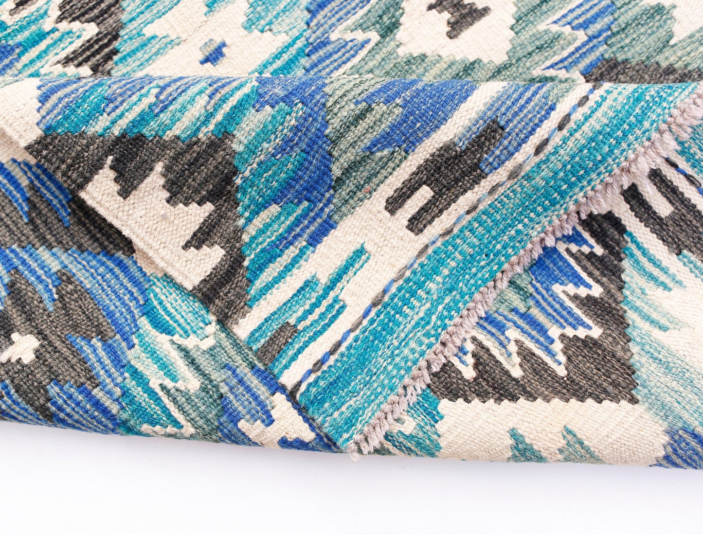 A handwoven Afghan Maimana kilim rug featuring a geometric pattern in shades of blue and cream.