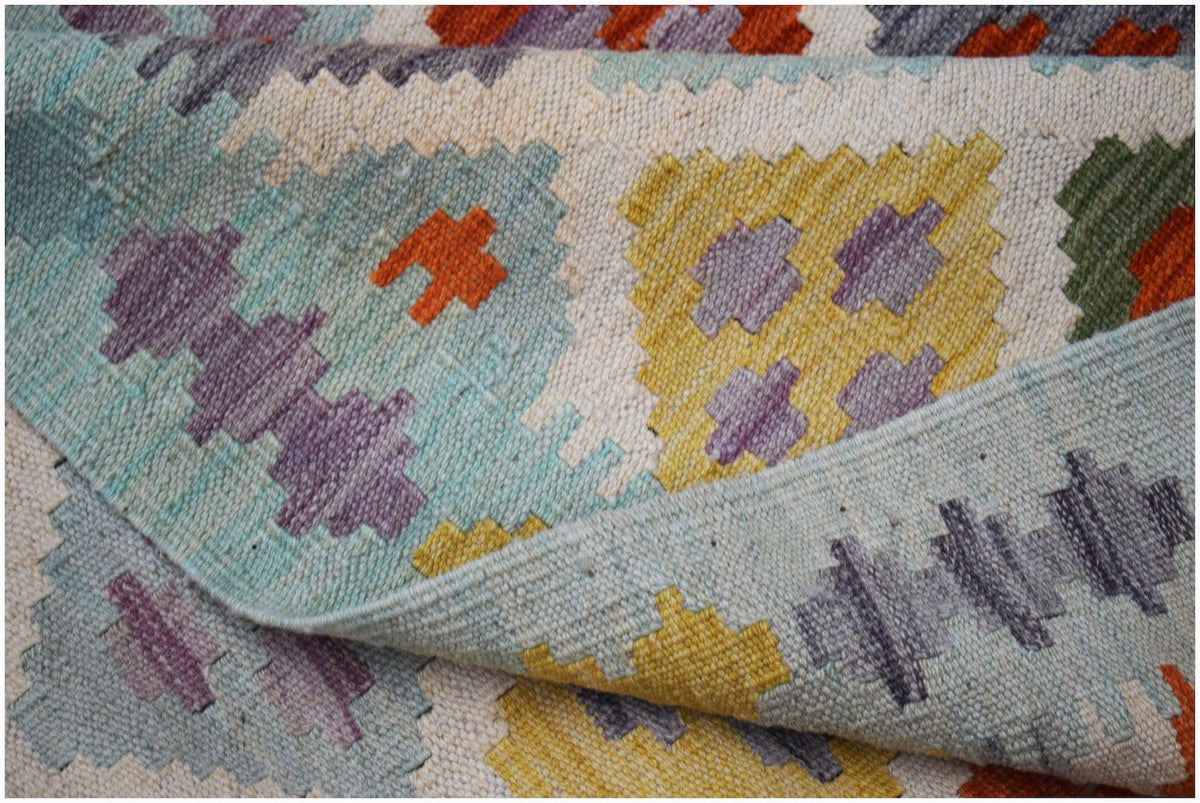 A handmade Afghan Maimana kilim rug featuring a geometric pattern in blue, yellow, and purple.