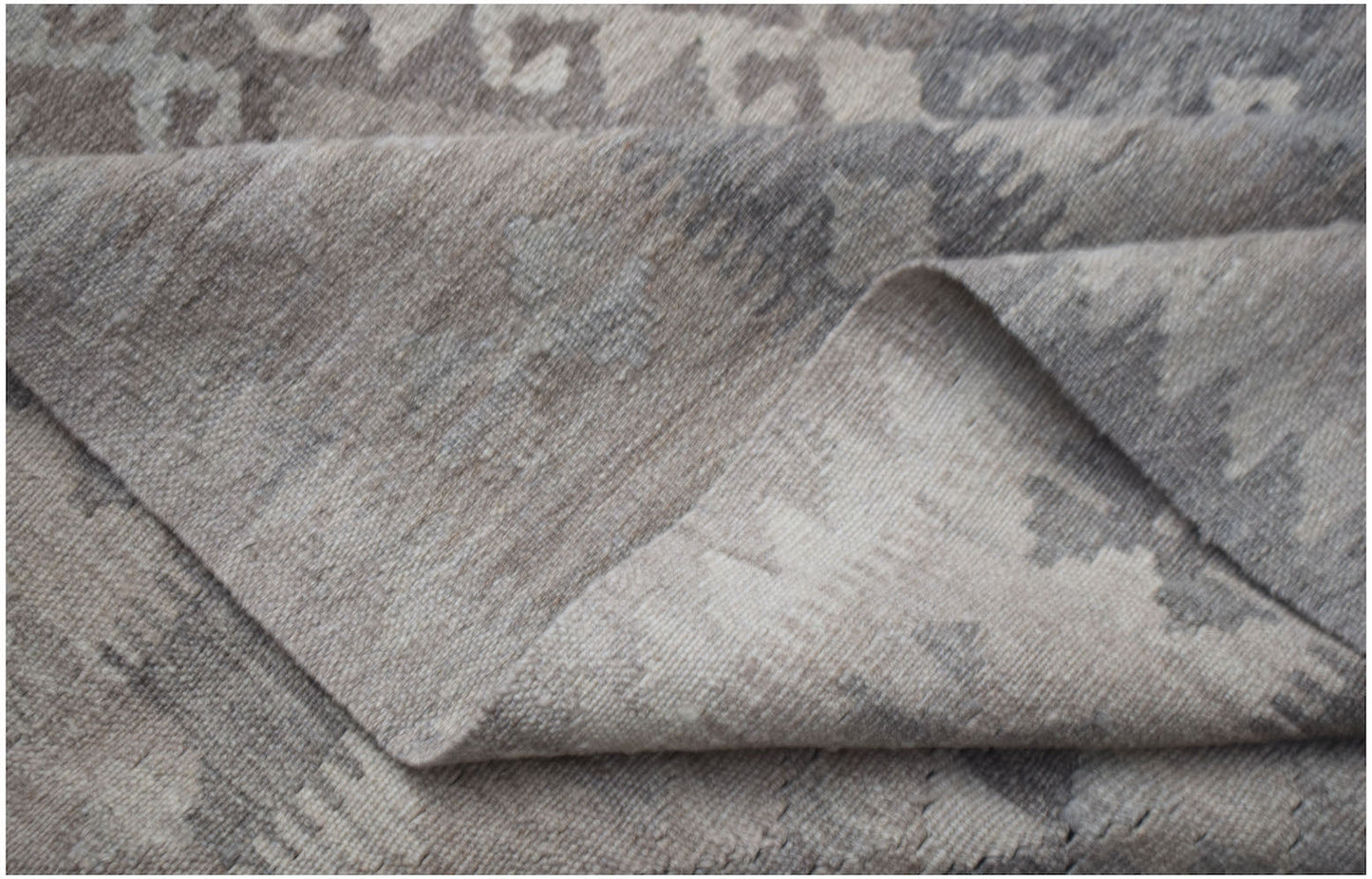 A handwoven Afghan Maiamana kilim rug featuring a flatweave texture and neutral geometric patterns.