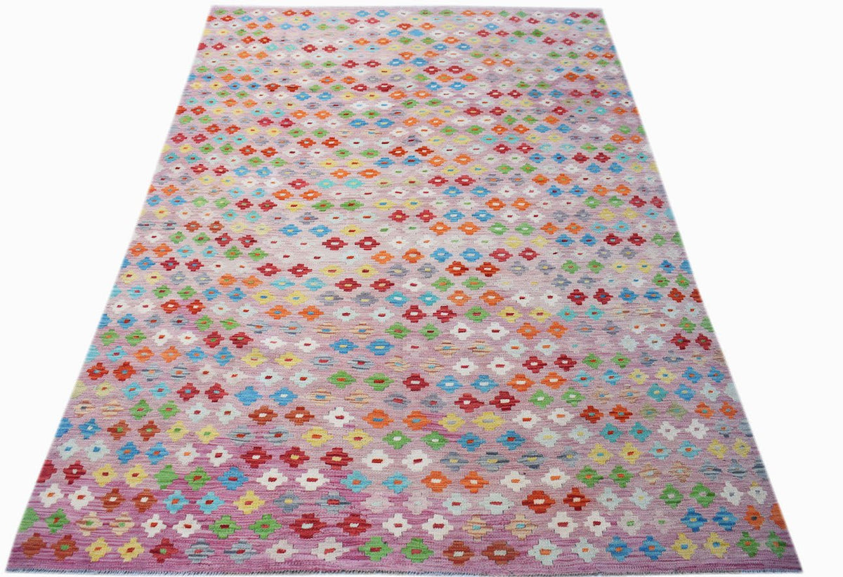 Handwoven Afghan Maimana kilim rug featuring a colorful geometric pattern on a pink background.