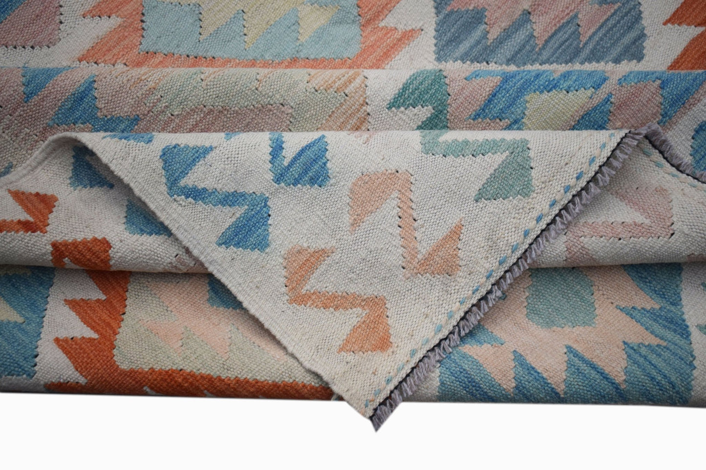 A handmade Afghan Maimana kilim rug featuring a geometric pattern in blue, orange, and cream wool.