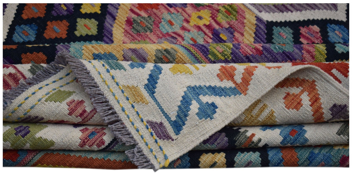 A handwoven Afghan Maimana kilim rug featuring colorful geometric patterns on a flat wool weave.