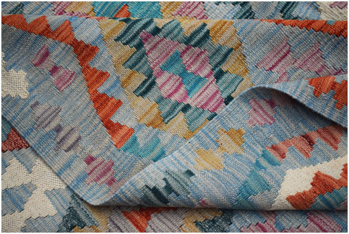 A handwoven Afghan Maimana kilim rug featuring a vibrant geometric pattern in wool.