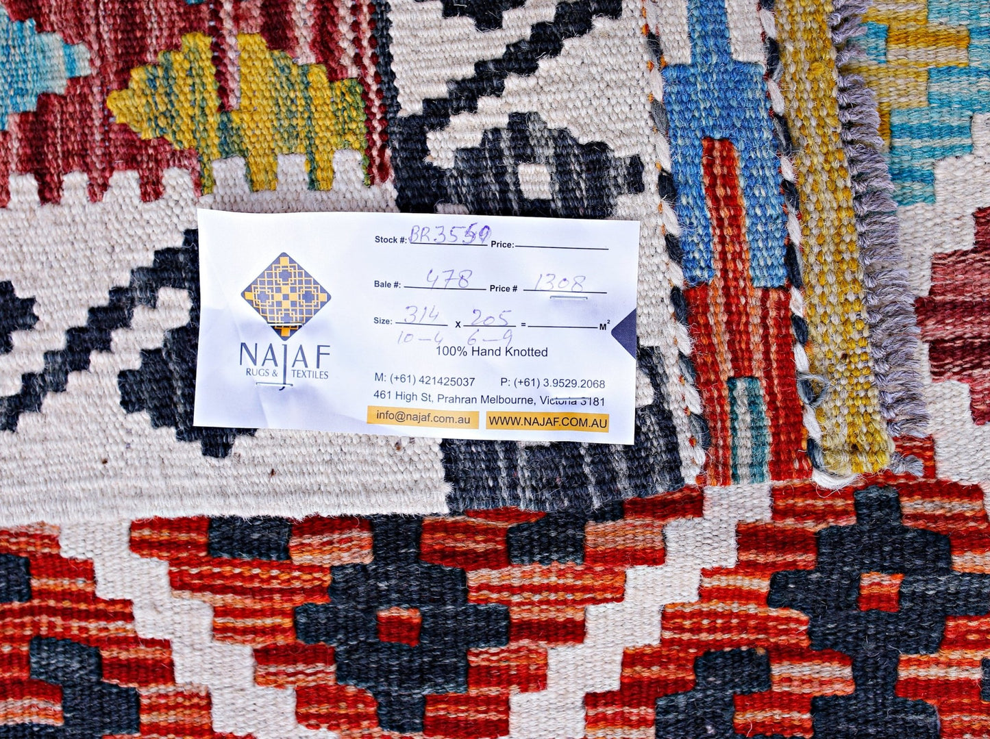 A handwoven Afghan Maimana kilim featuring a vibrant geometric pattern in red, blue, and yellow.