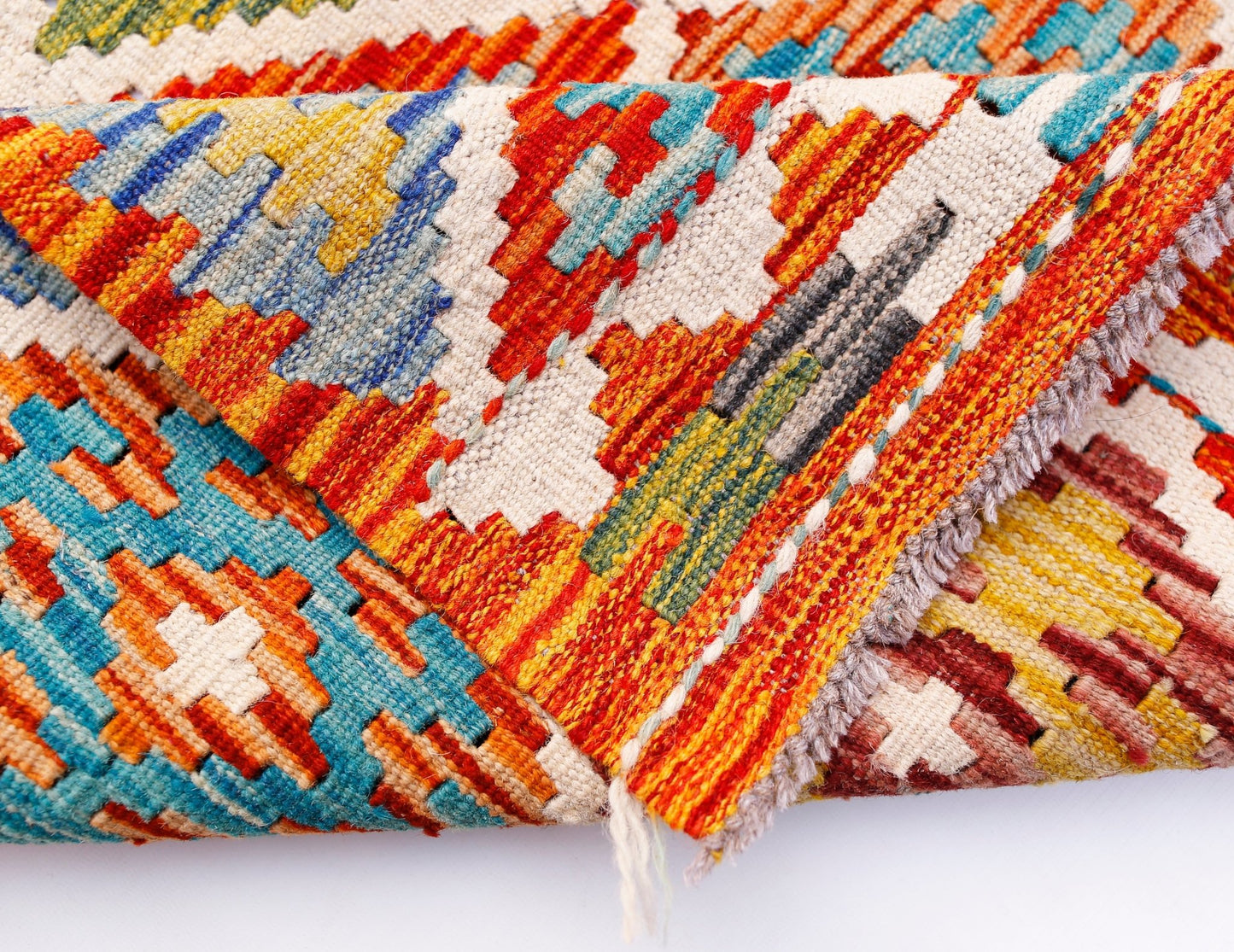A folded Afghan Maimana Kilim runner featuring vibrant geometric patterns in wool.