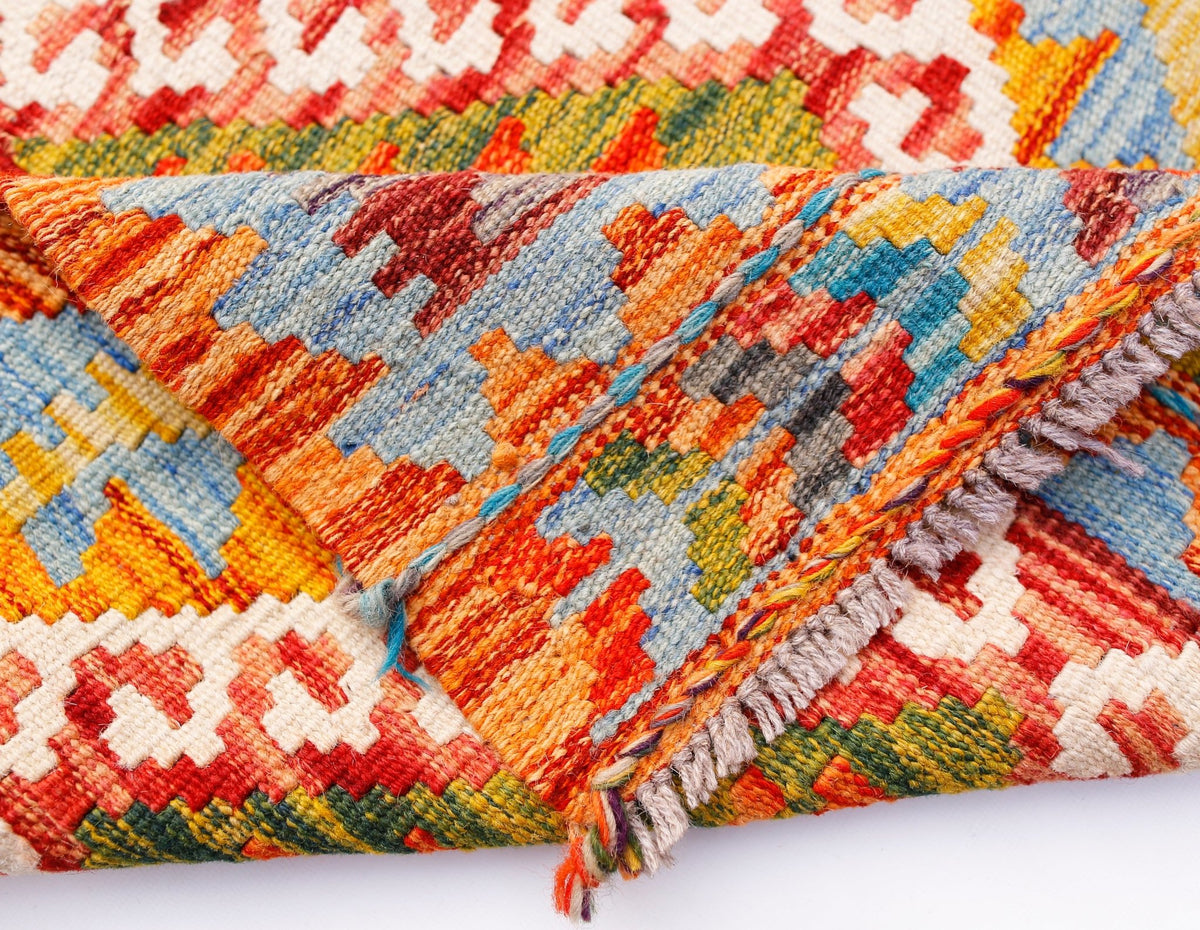 A handmade Afghan Maimana kilim runner featuring a vibrant geometric pattern in wool.