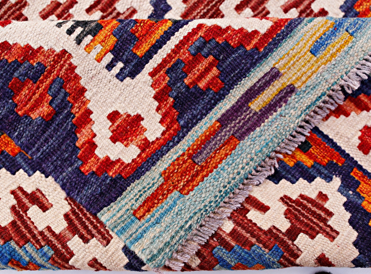 A handmade Afghan Maimana kilim runner featuring a geometric pattern in red, blue, and cream.