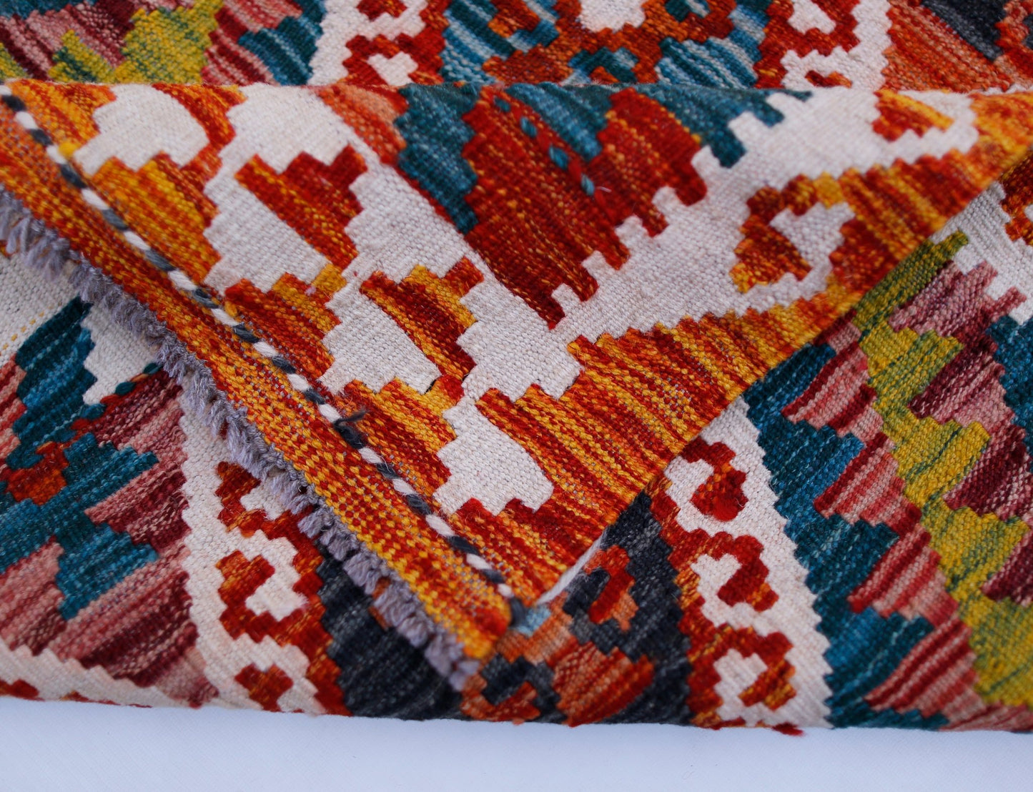 A handwoven Afghan Maimana kilim runner featuring a vibrant geometric pattern in wool.