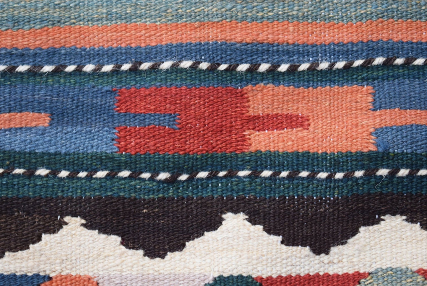 A close-up of a handmade Afghan Maimana kilim runner featuring geometric patterns in wool.