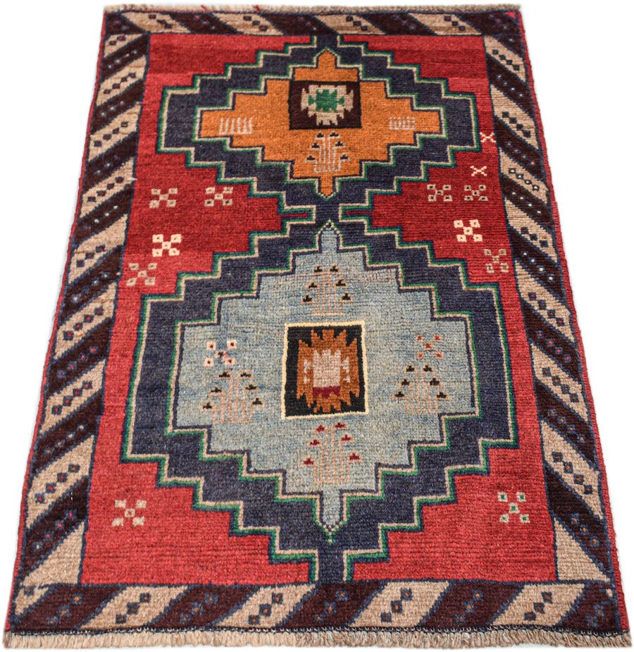 Handmade Afghan Pashm rug featuring a geometric tribal pattern in red, blue, and orange wool.