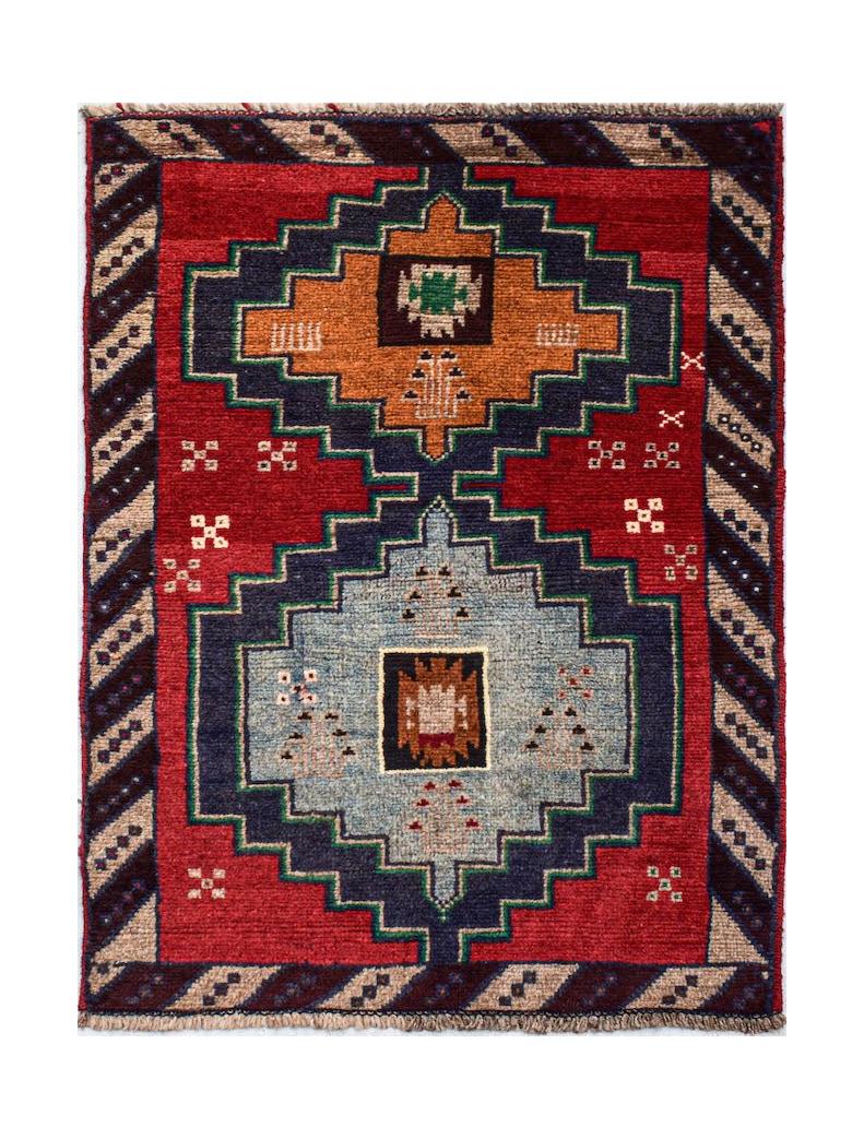 Handmade Afghan Pashm rug featuring a geometric tribal pattern in red, blue, and orange wool.