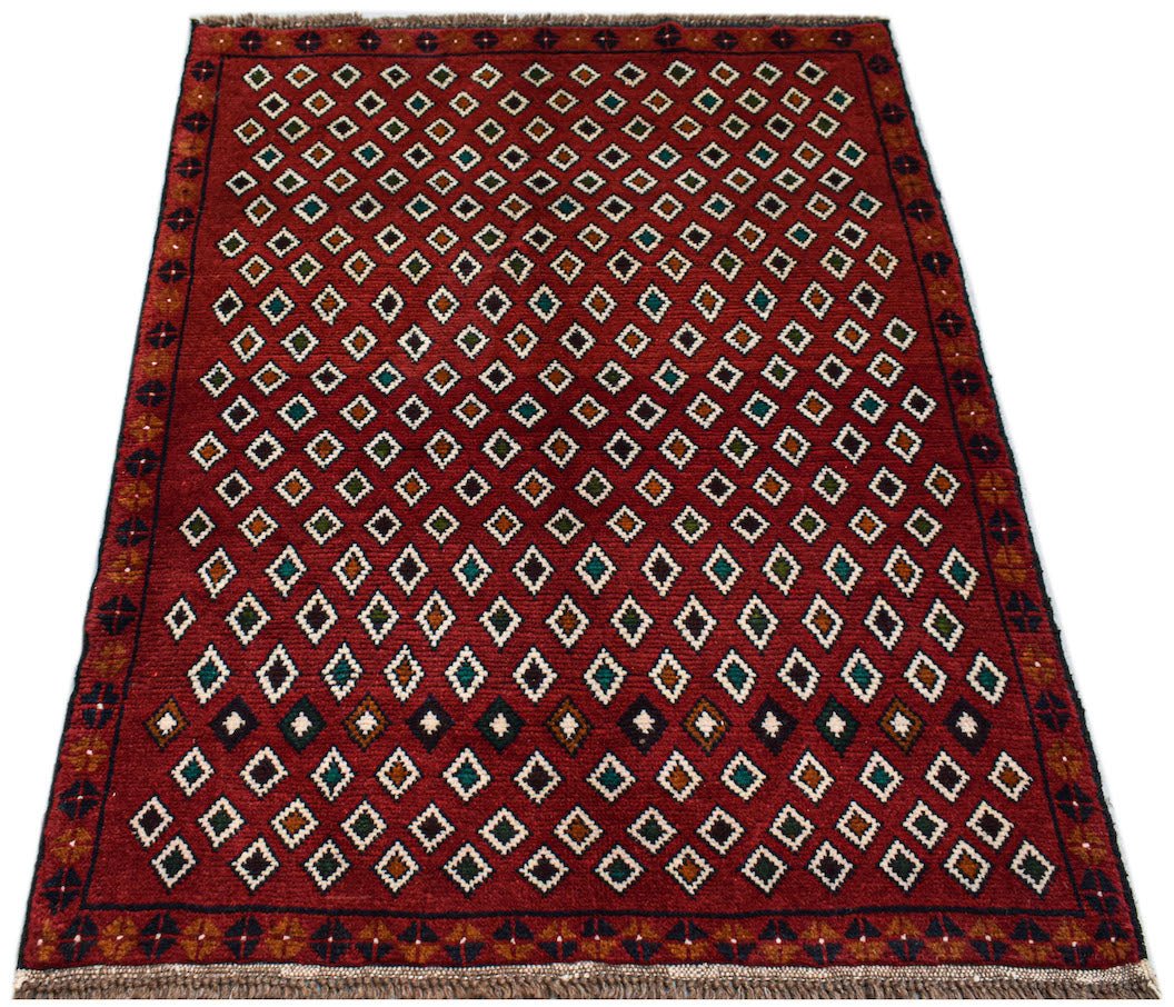 Handmade Afghan Pashm rug featuring a repeating diamond pattern in red, blue, and ivory wool.