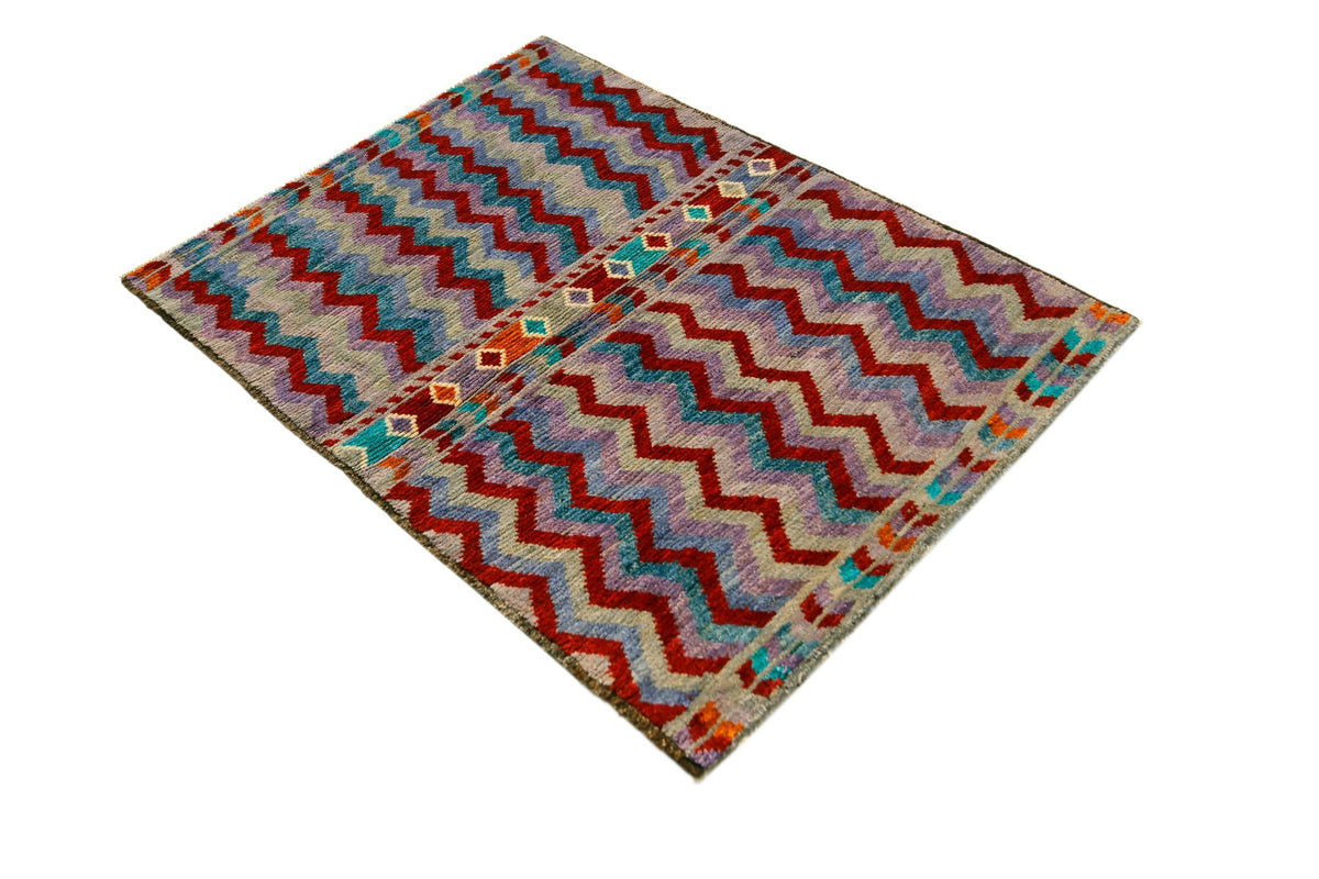 Hand-knotted Afghan Pashm wool rug featuring a dense, shaggy pile with bold red and blue geometric zigzag patterns.