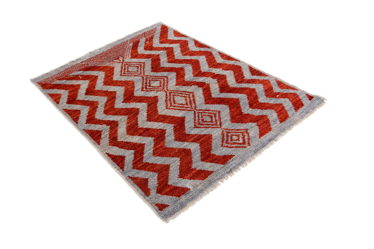 Hand-knotted Afghan Pashm wool rug with a bold red and grey geometric chevron pattern and fringed edges.