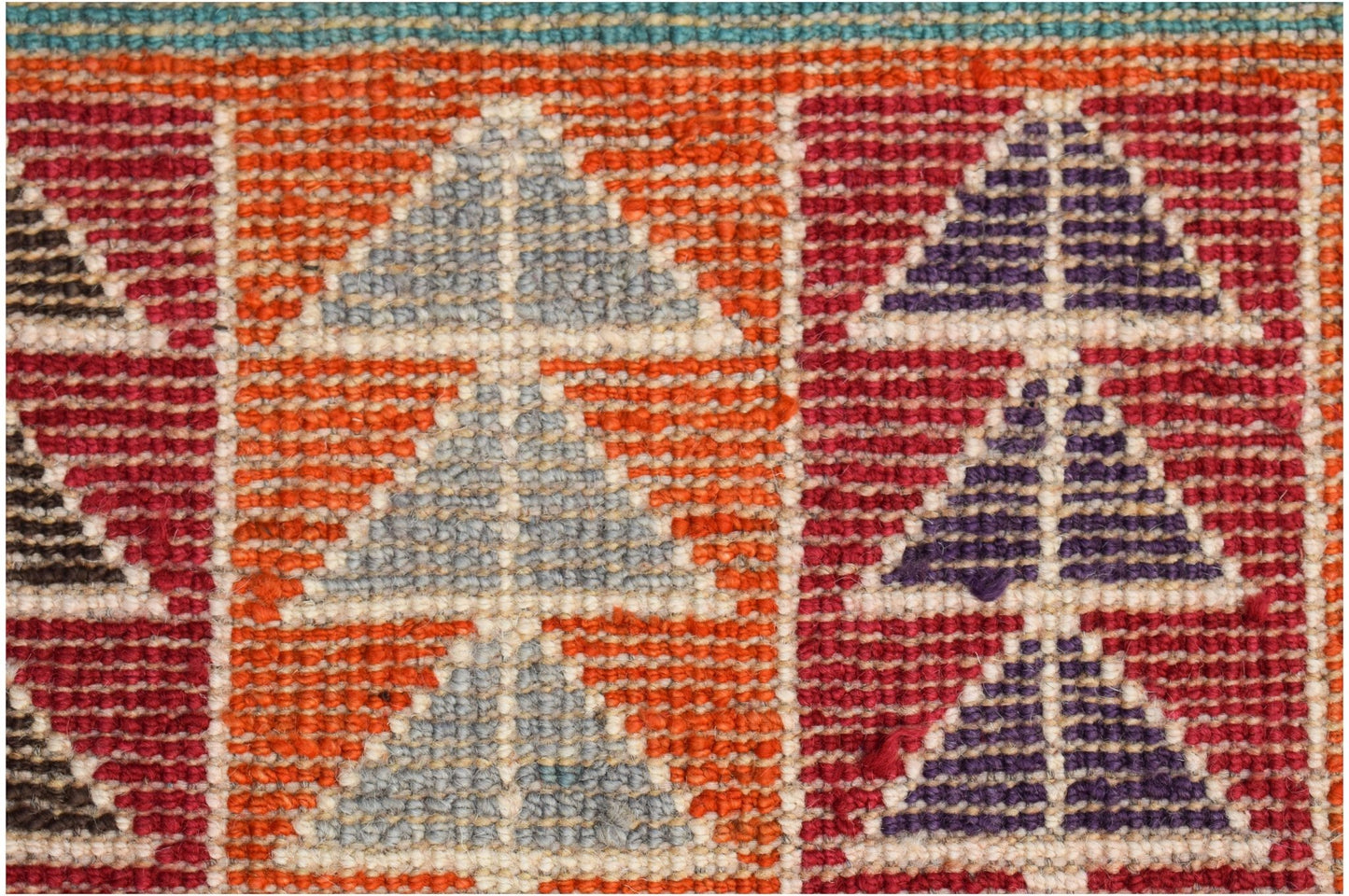 A close-up of a hand-knotted Afghan wool rug featuring geometric triangle patterns in vibrant colors.