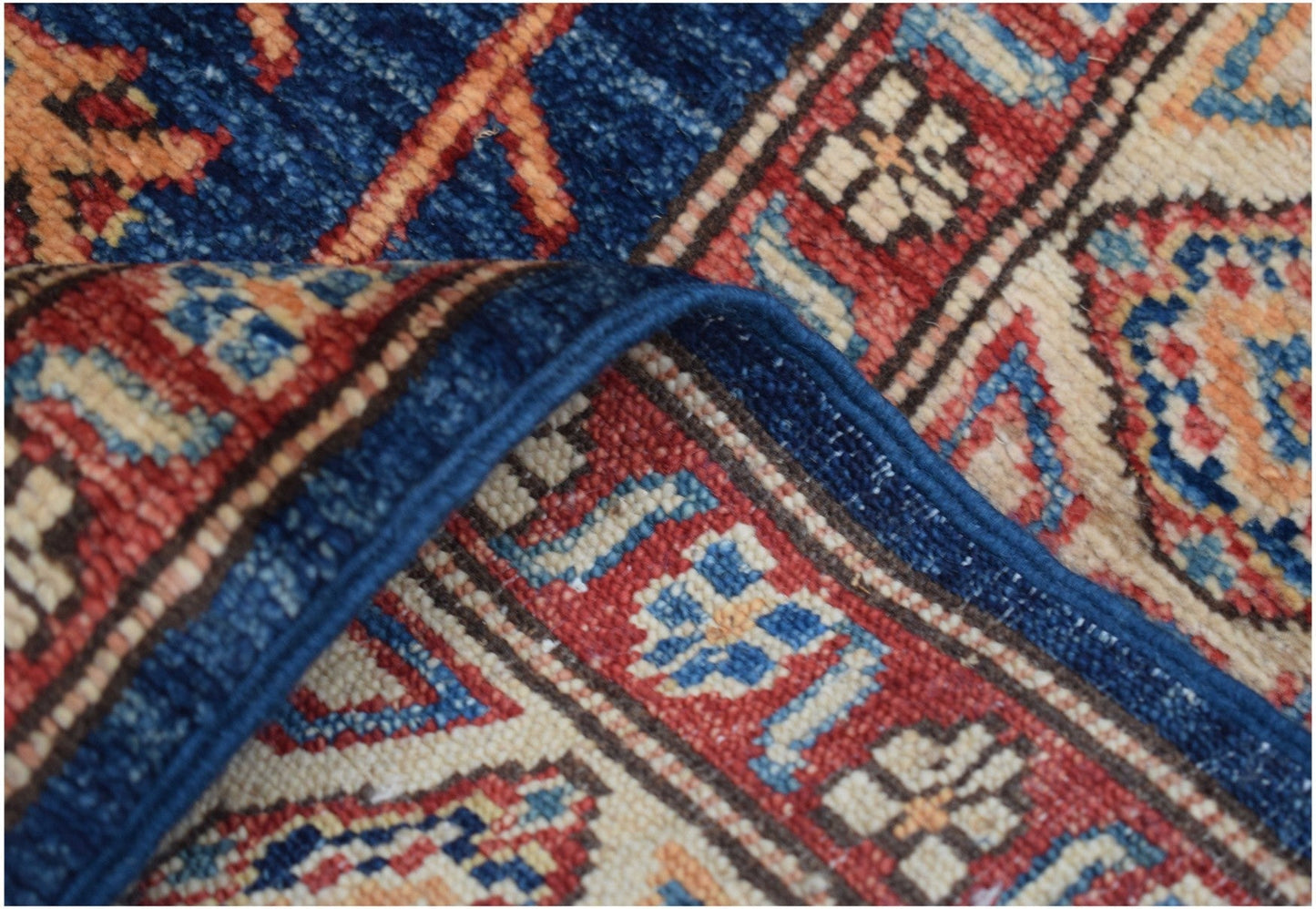 A close-up view of a handmade Afghan Kazakh runner featuring a traditional geometric pattern.