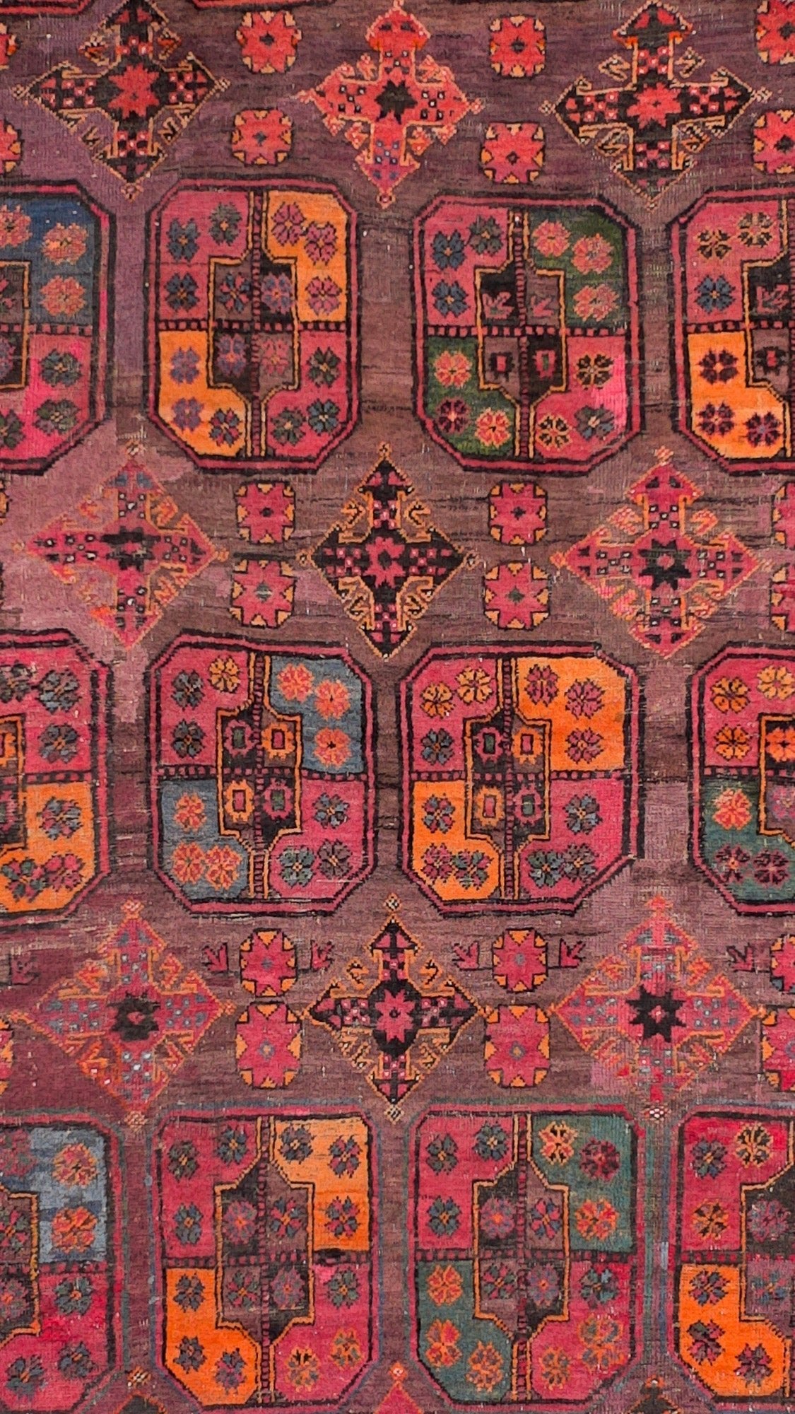 An antique Afghan Baluch rug featuring a repeating geometric pattern in deep red, brown, and blue.