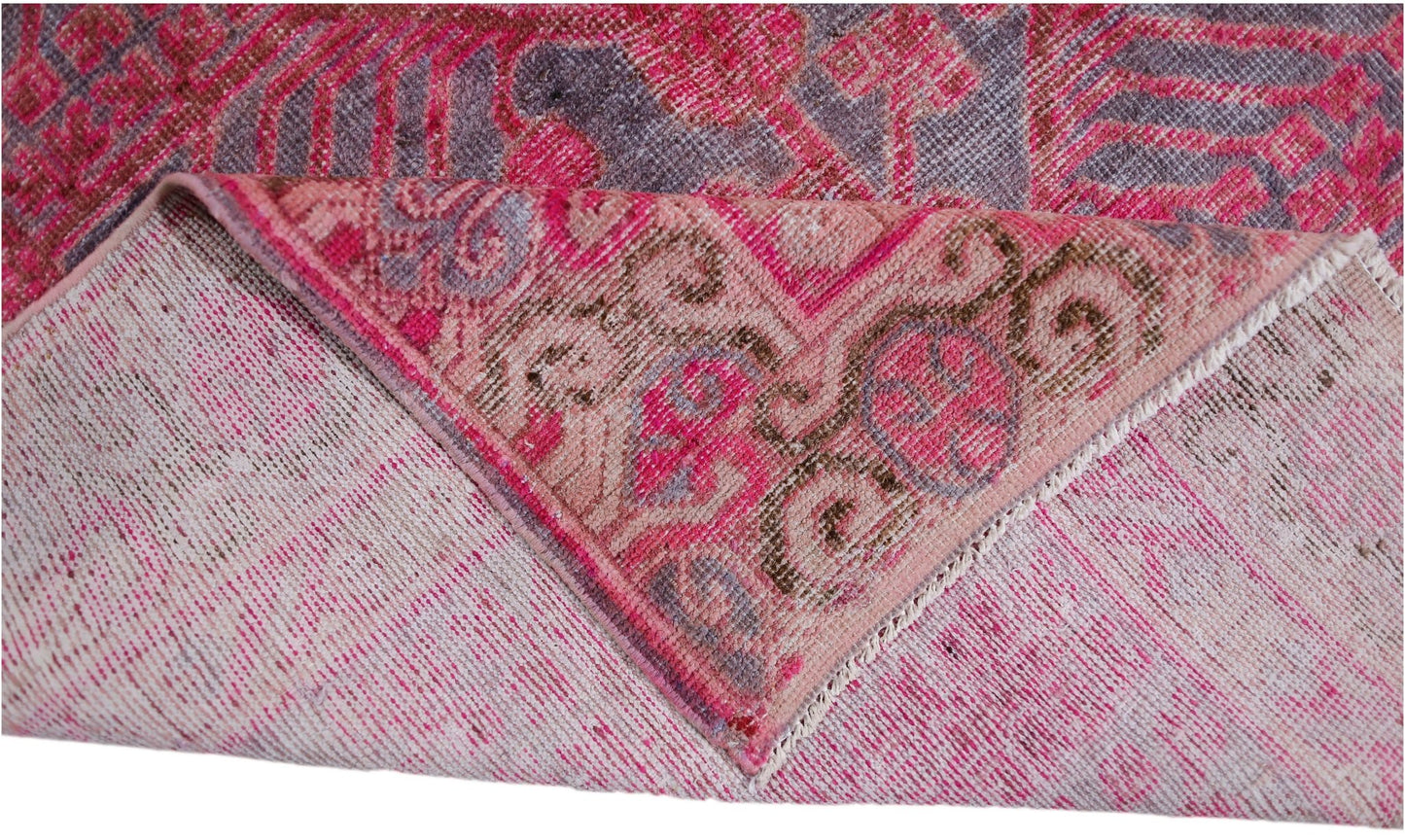 An antique handwoven Khotan rug featuring an intricate pomegranate pattern in vibrant pink tones.