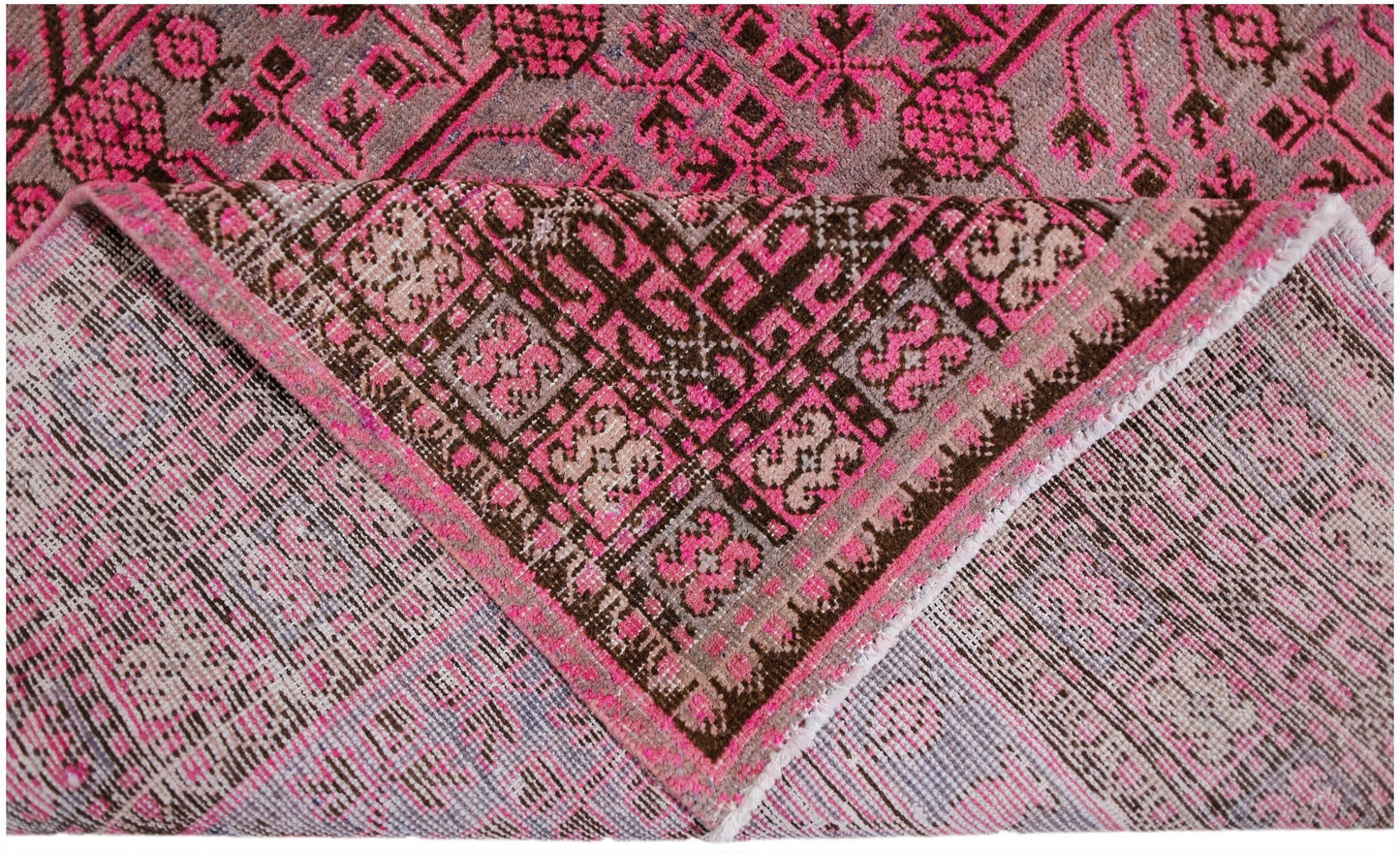 An antique handwoven Khotan rug featuring an intricate pomegranate pattern in vibrant pink.