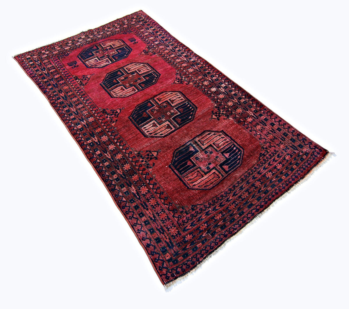 Antique Turkmen Ersari rug with red field, blue elephant's foot guls, and hand-knotted wool pile on a white background.