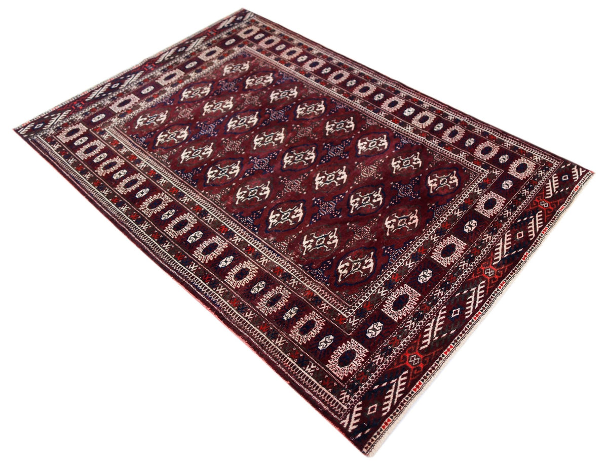 Antique Turkmen Tekke rug featuring deep red tones and repeating quartered gul motifs with intricate geometric borders.
