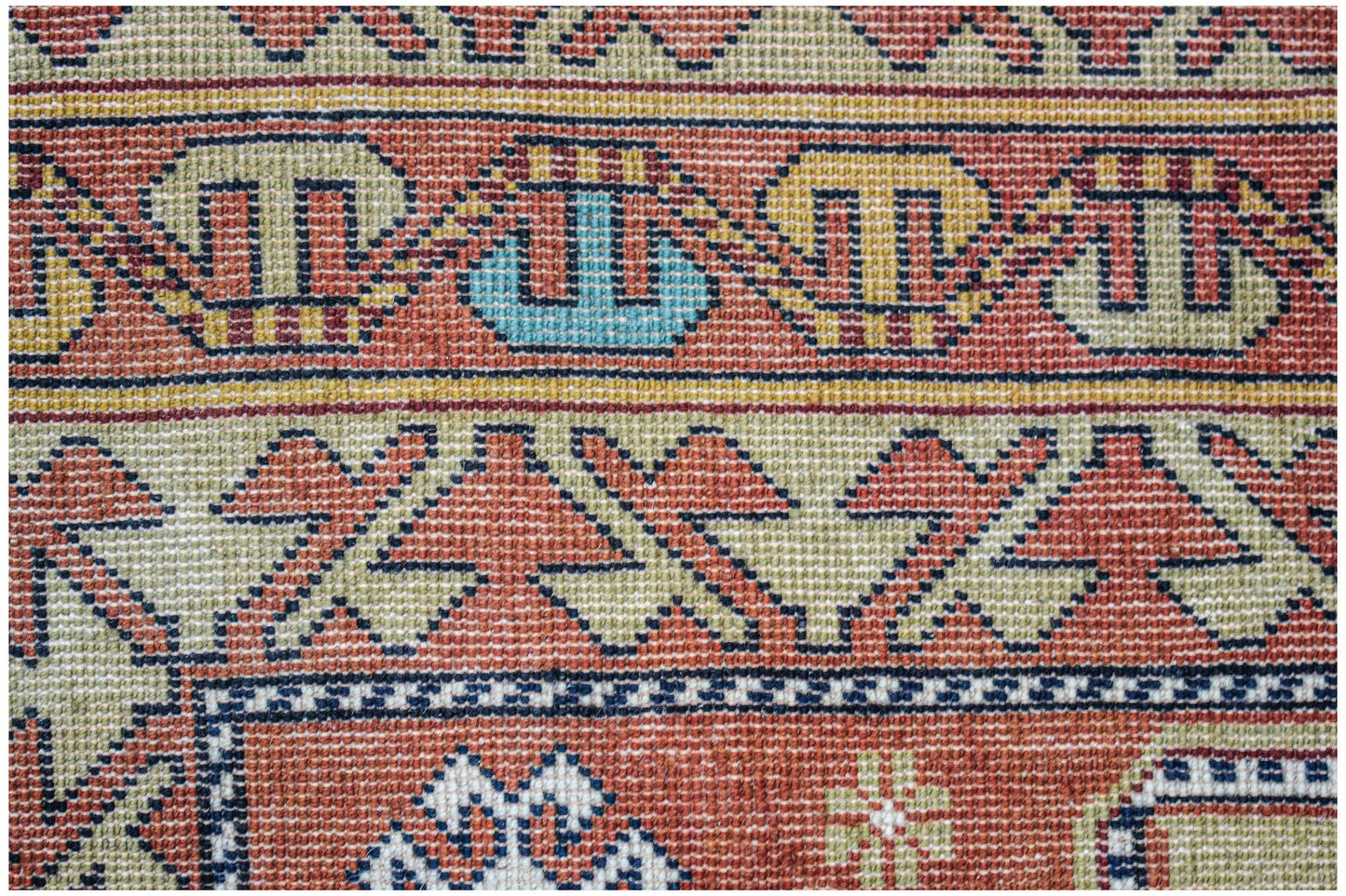 A vintage handwoven Caucasian rug featuring geometric patterns in red, blue, and beige tones.