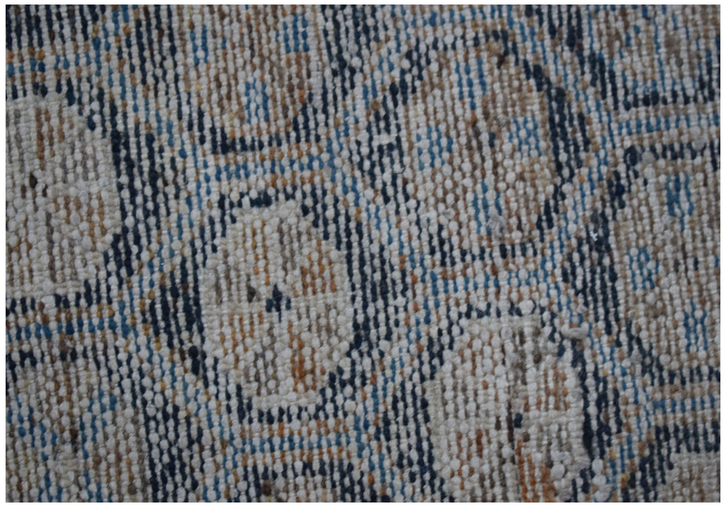 A close-up view of a vintage Persian rug featuring a faded geometric pattern in blue and tan.