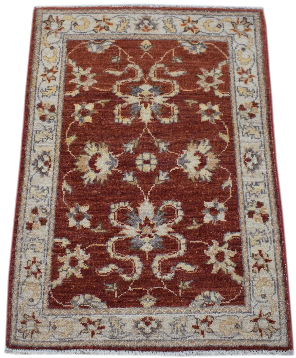 Miniature Afghan Chobi rug in terracotta red with intricate floral motifs, a cream border, and a hand-knotted wool pile.