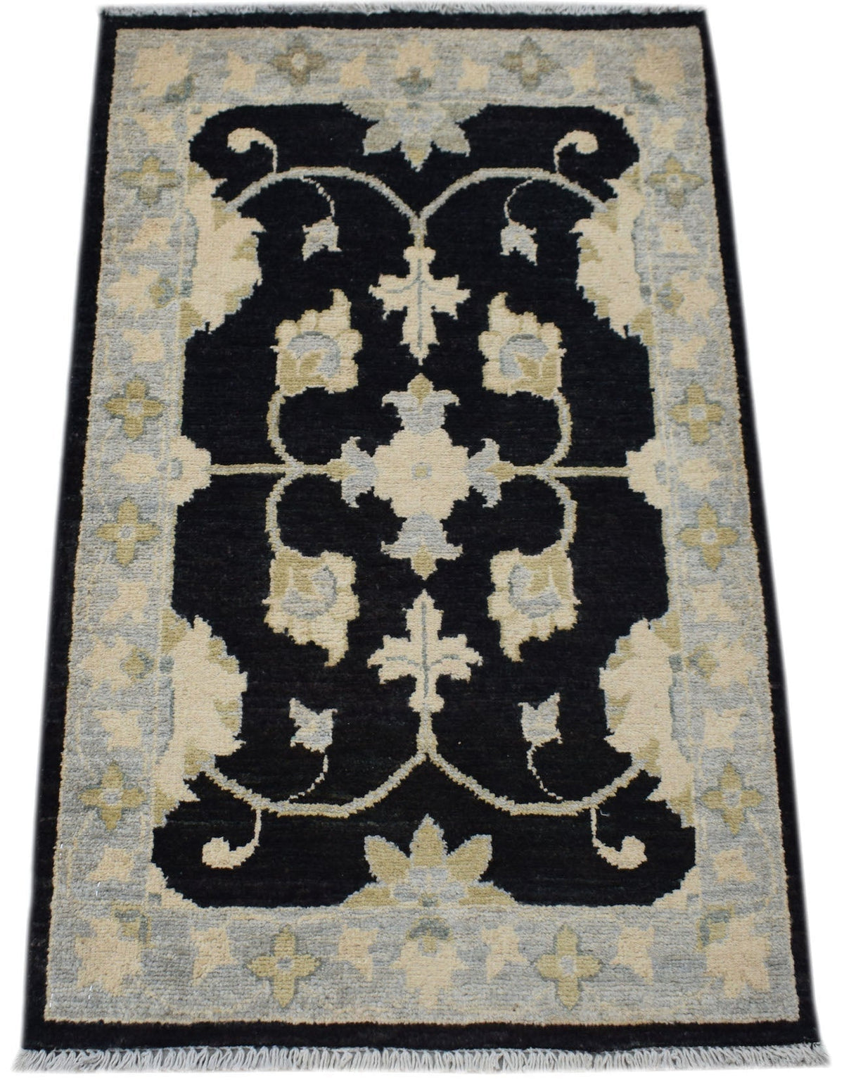 Hand-knotted Afghan Chobi rug with a black field, cream floral motifs, and a detailed border with short white fringe.