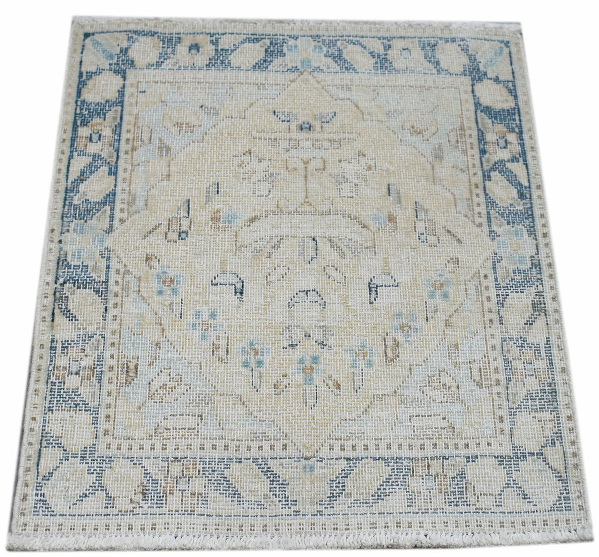Mini vintage Persian Kerman rug featuring a cream field with a blue floral medallion and intricate border with soft pile.