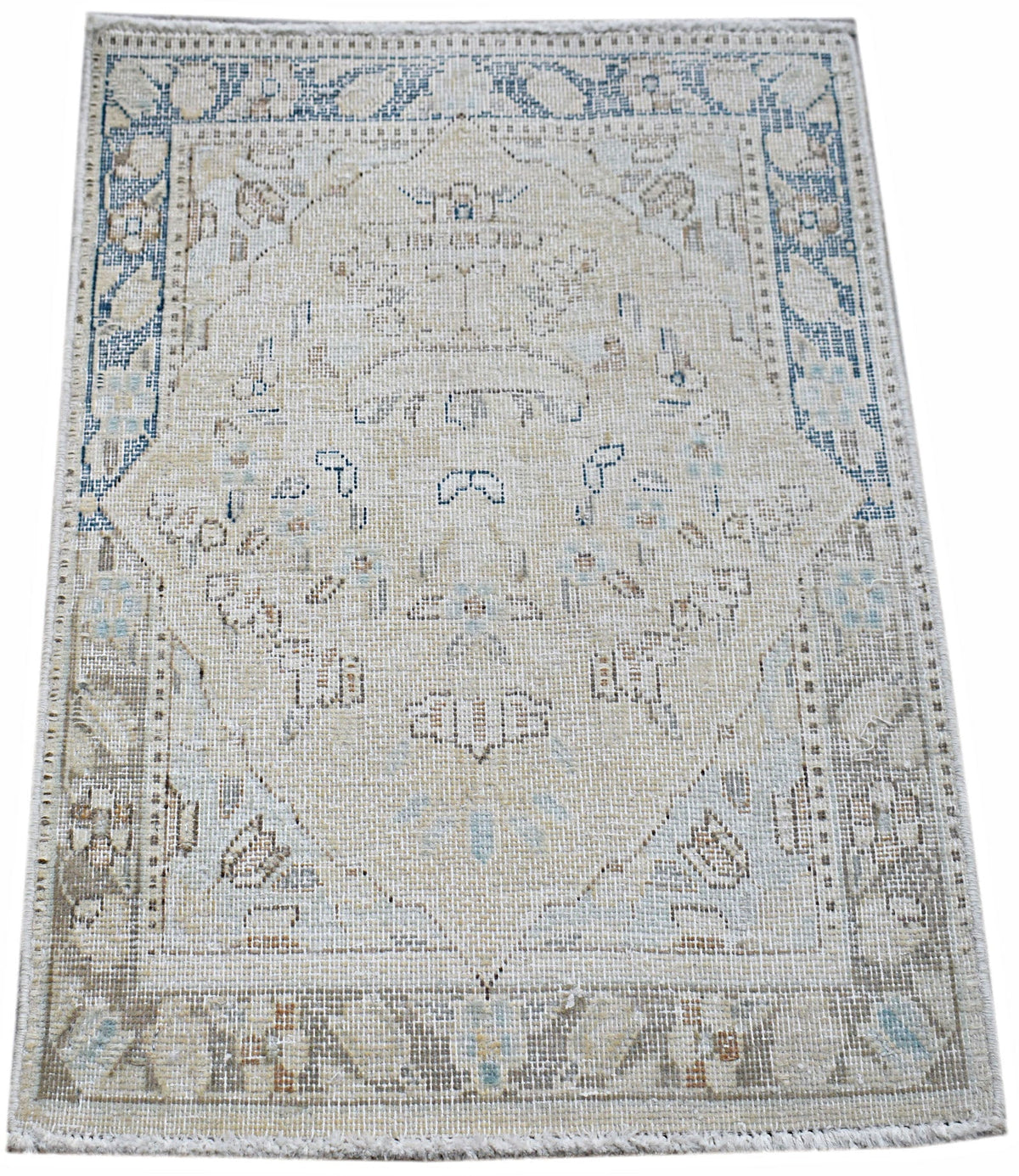 Mini vintage Persian Kerman rug featuring a central floral medallion in soft blue, cream, and beige tones with a fringed edge.