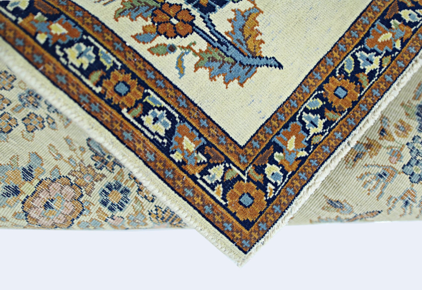 A folded vintage Persian Sarouk rug featuring a floral pattern in blue, orange, and cream tones.