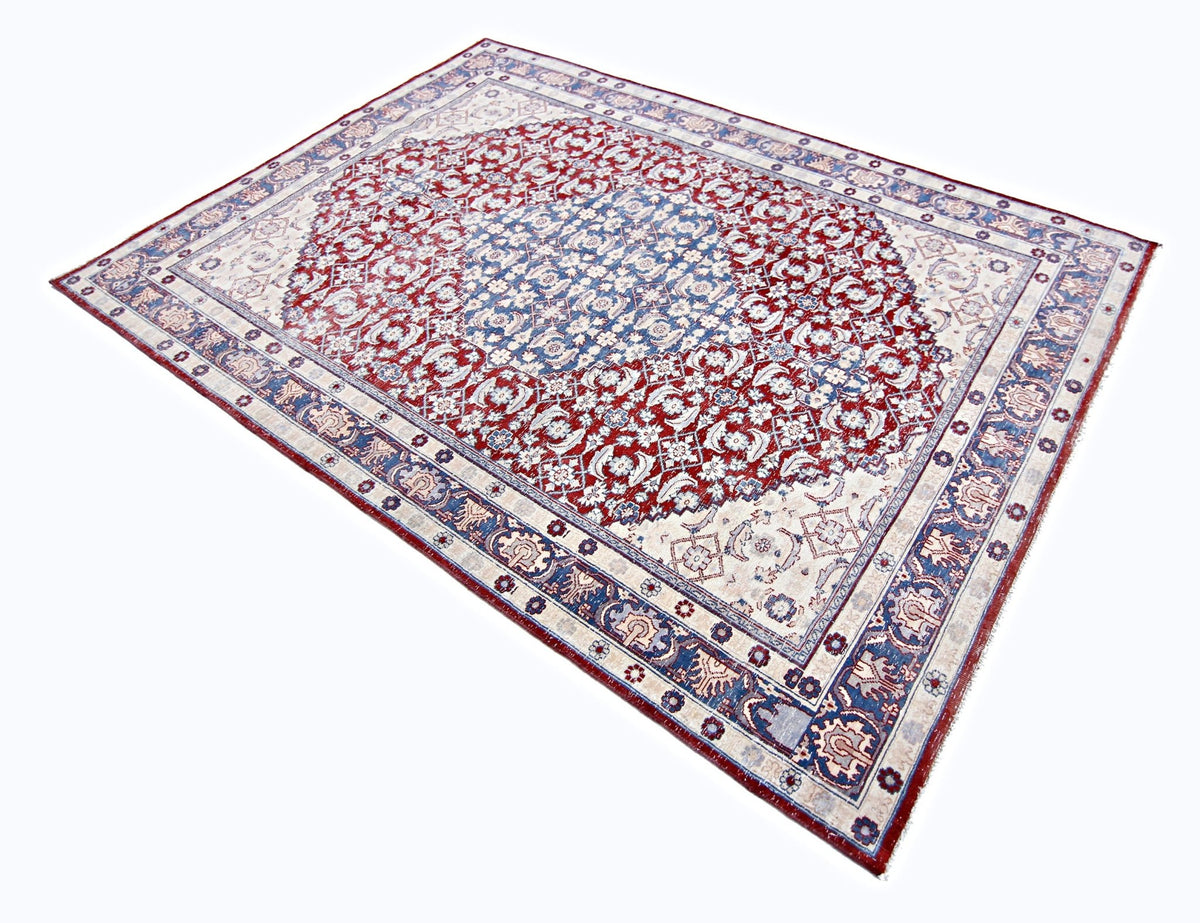 Traditional Pakistani rug with a central blue medallion, intricate red floral patterns, and a detailed geometric border.