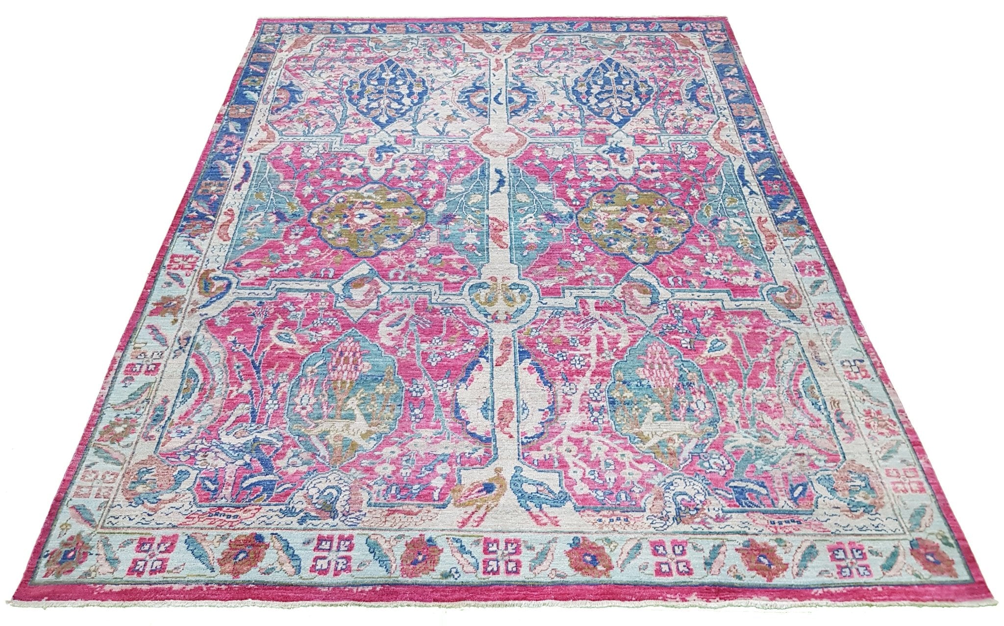 A handmade Afghan rug featuring a vibrant pink and blue Tree of Life pattern on a low pile.