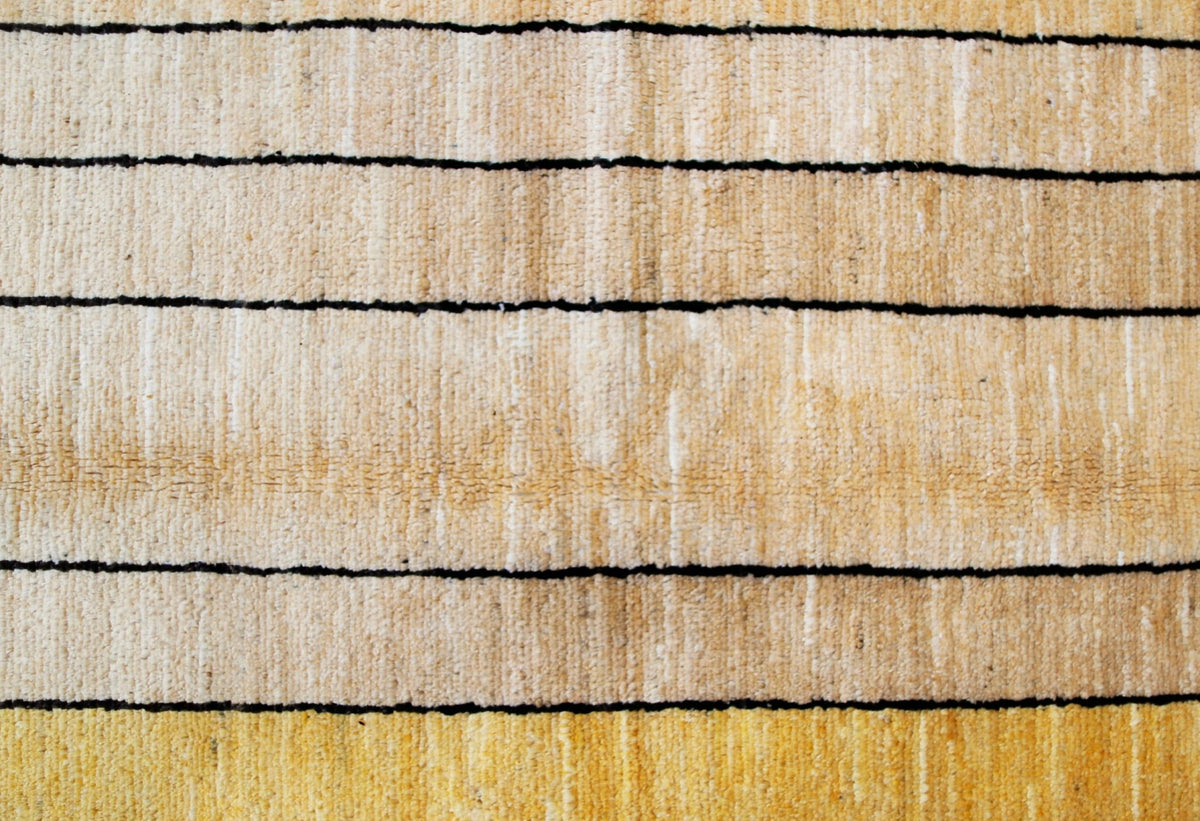 Close-up of a hand-knotted Afghan wool rug featuring horizontal cream and golden-yellow stripes with thin black lines.