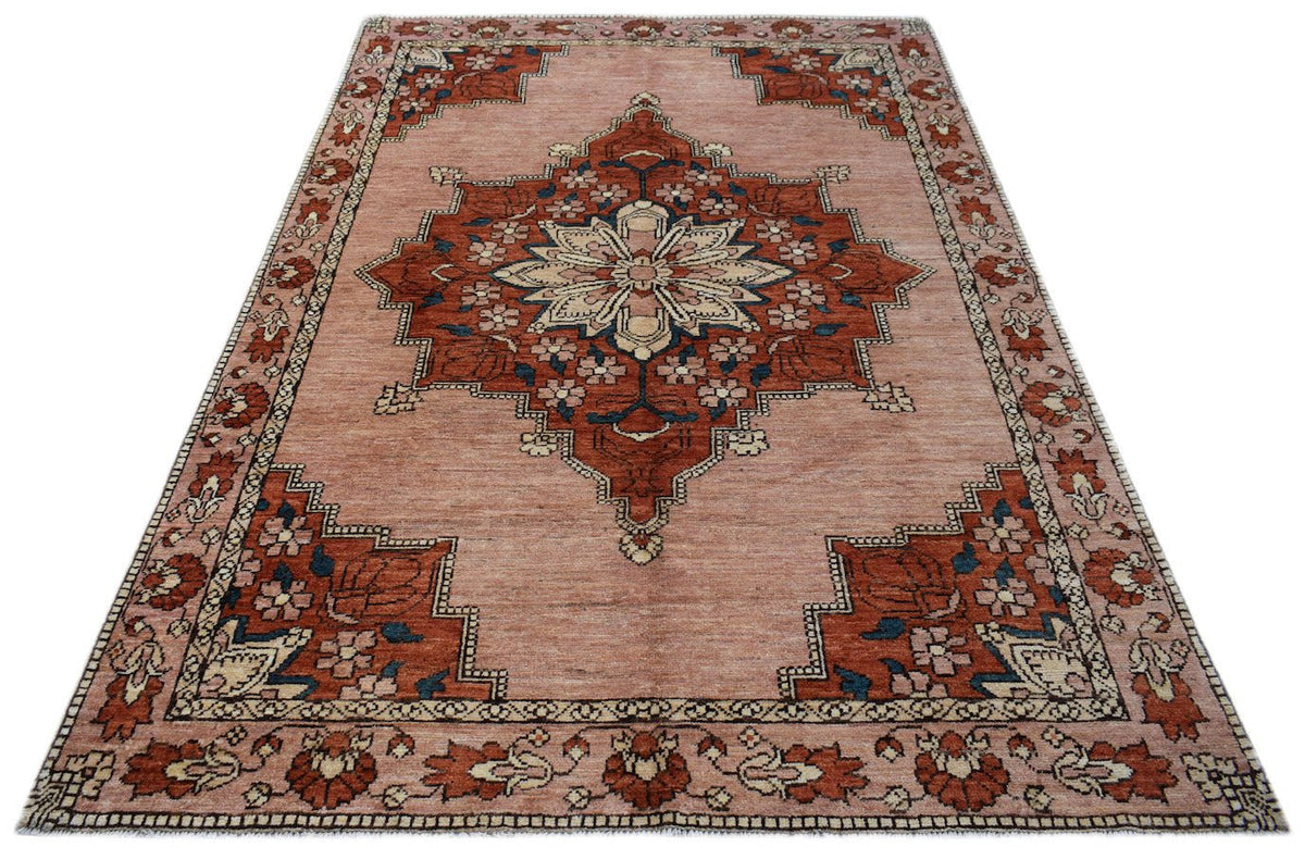 Handmade Afghan Kohi wool rug featuring a central floral medallion on a dusty pink background.