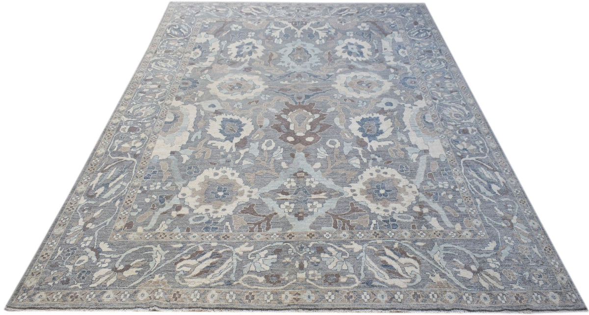 A handwoven transitional Oushak rug featuring a floral pattern in shades of blue, grey, and cream.