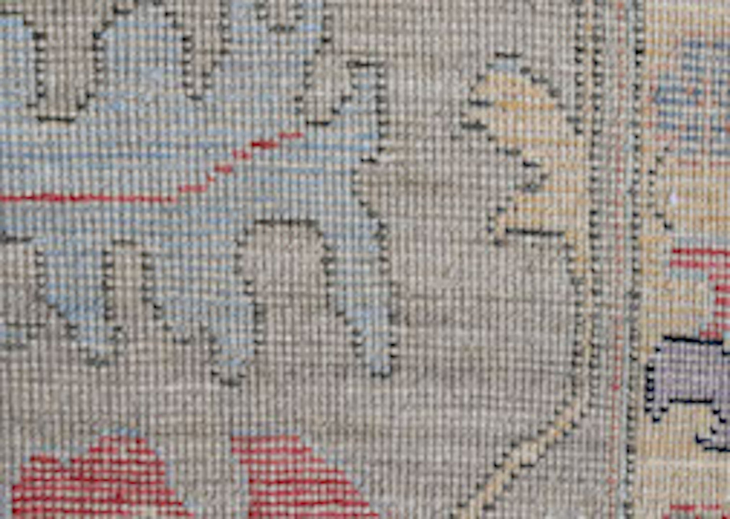 A close-up view of a handwoven wool rug featuring intricate floral patterns in red and blue tones.