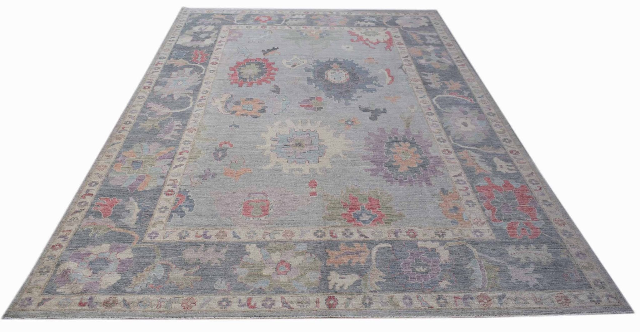 A handwoven transitional Oushak rug featuring a floral pattern in muted tones on a grey background.