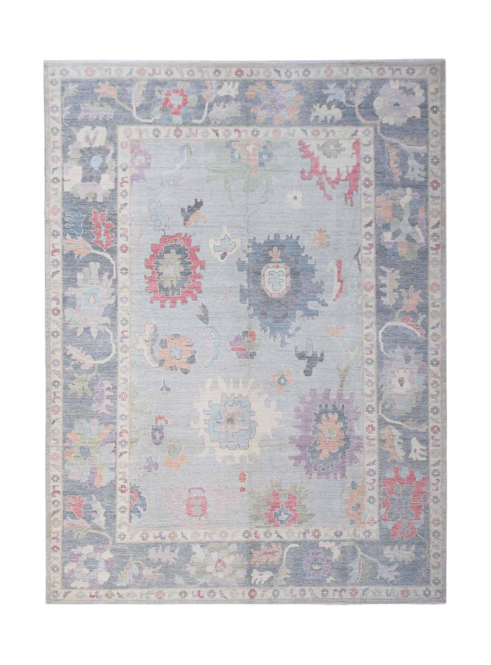 A handwoven transitional Oushak rug featuring a floral pattern in soft blue and multi-colored tones.