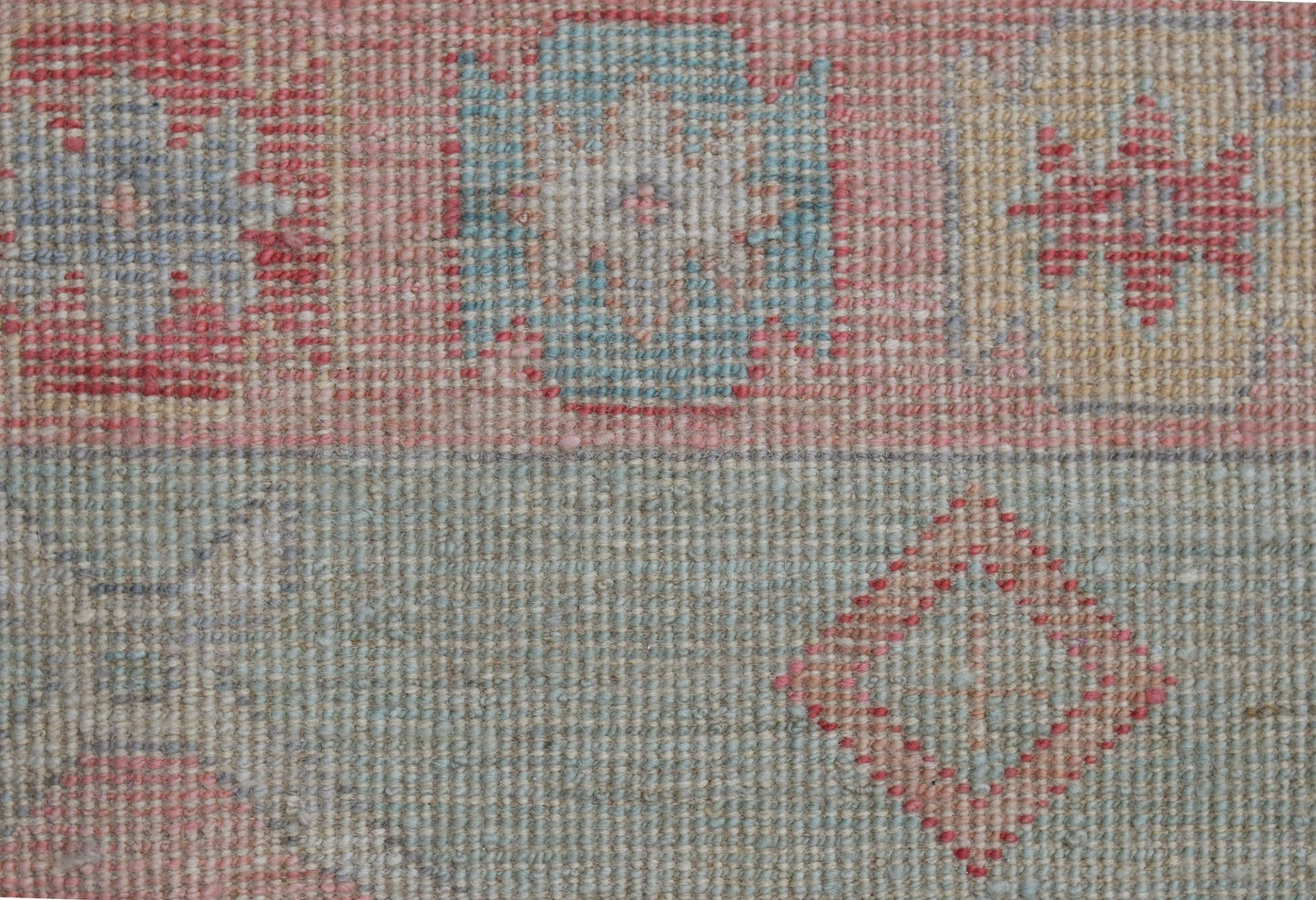A handwoven wool runner featuring a transitional Oushak pattern in soft blue and red tones.