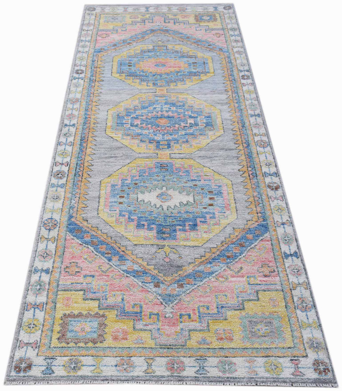 Transitional Oushak runner featuring soft blue, pink, and yellow medallions on a grey field in a hand-knotted wool design.