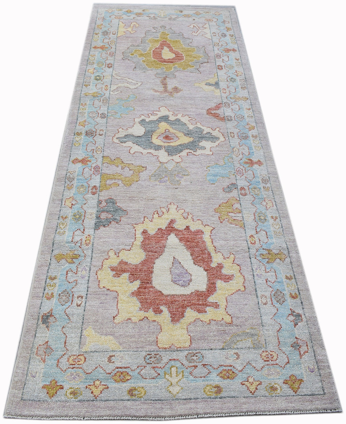 Hand-knotted Oushak runner in soft lavender with multicoloured palmette and medallion motifs on a long, narrow field.