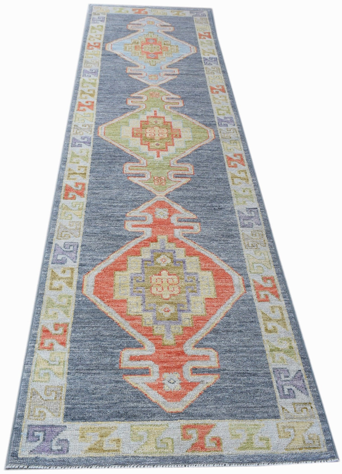 A handwoven transitional Oushak runner featuring geometric medallions on a blue field.