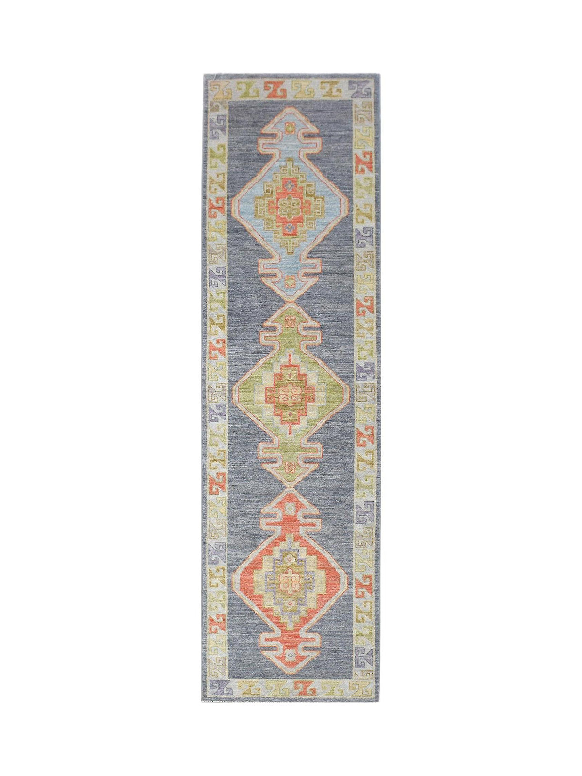 A handwoven wool runner rug featuring three geometric diamond medallions on a dark grey field.