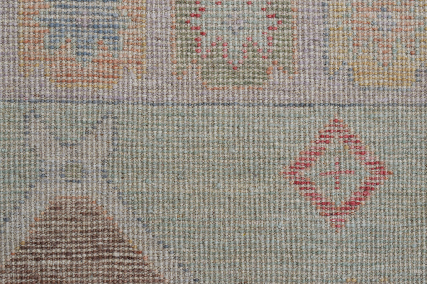 A handwoven wool runner featuring a transitional pattern with geometric motifs in muted tones.