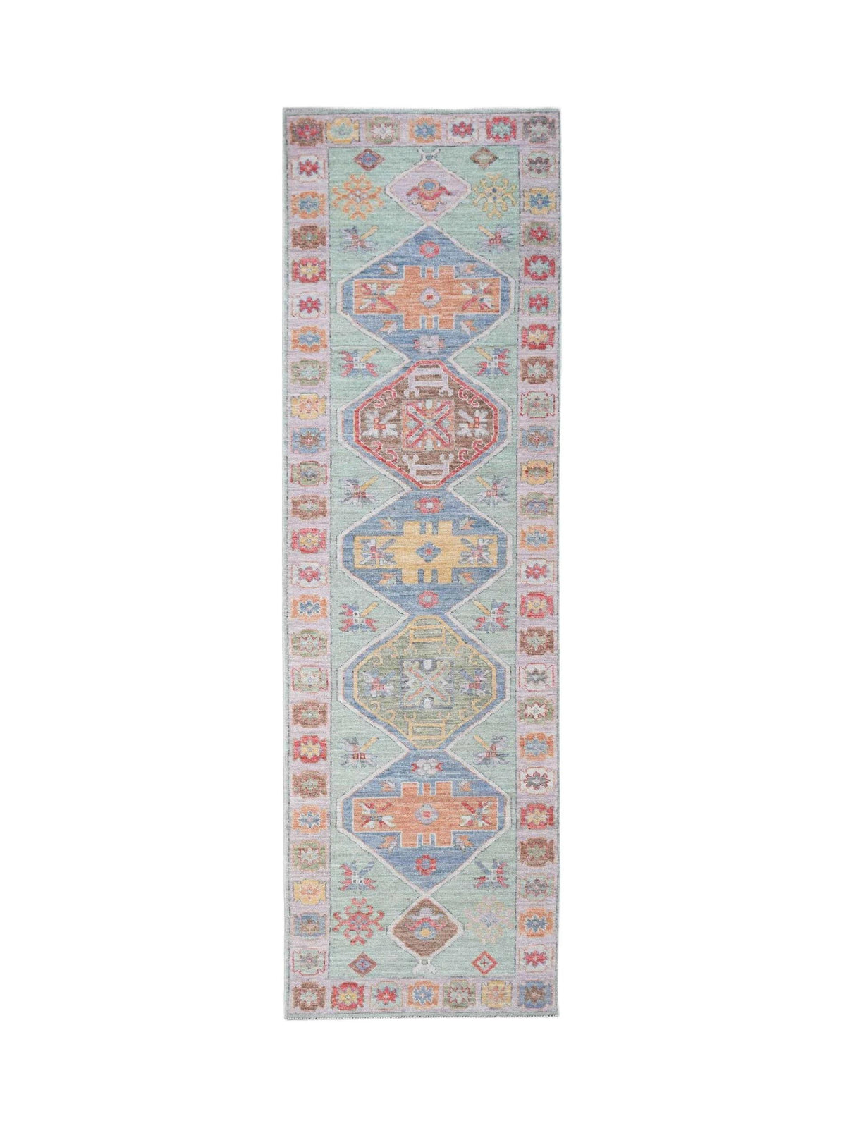 Transitional Oushak runner with a soft green field, colourful geometric medallions, and a detailed floral border.